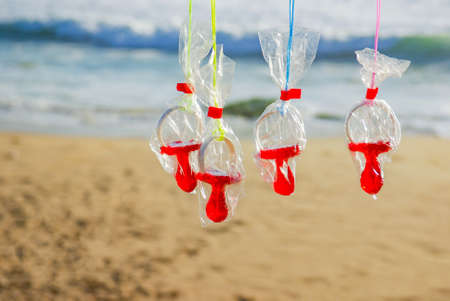 A row of four pacifier candies wrapped in plastic and hanged over a beach backgroundの写真素材