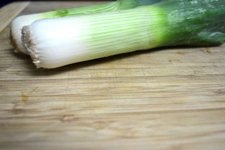 two leeks on wood cutting boardの写真素材