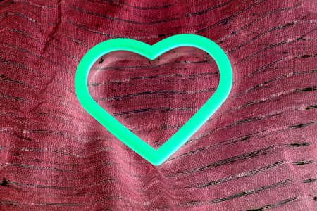 glow in the dark heart isolated on burgundy fabricの写真素材