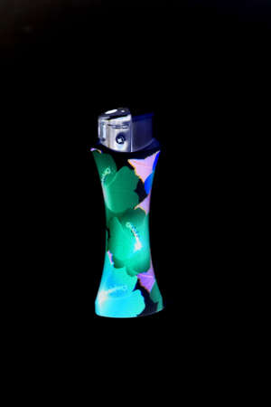 glow in the dark flower decorated lighter isolated on black background close upの写真素材