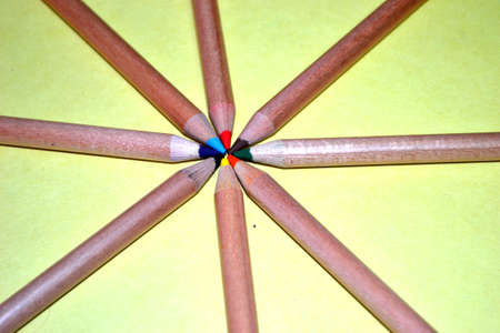 wooden pencil crayons coming to a point isolated on pale yellow background close upの写真素材