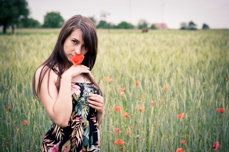 Beautiful young girl on the field with poppy flowersの写真素材