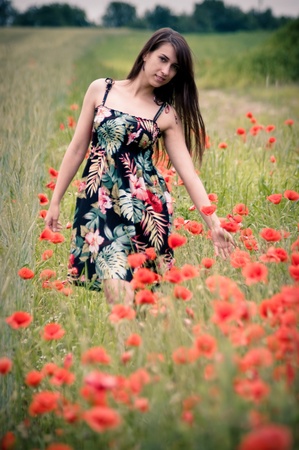 Beautiful young girl on the field with poppy flowersの写真素材