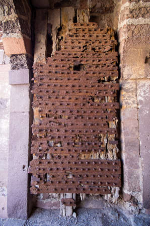 Old wooden gate covered by rusty metalの写真素材