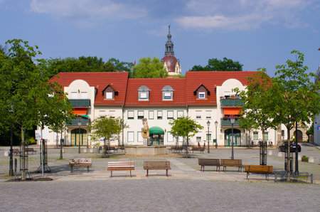 Discover tranquility in this charming European town square. A picturesque setting with a fountain, benches, and classic architecture, perfect for travel and lifestyle content.の写真素材