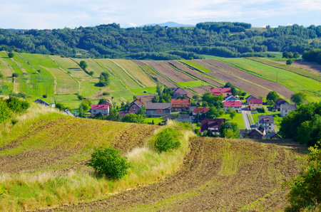 Discover a tranquil village nestled among rolling farmland. This peaceful landscape evokes a sense of rural charm and idyllic beauty, perfect for travel or lifestyle themes.の写真素材