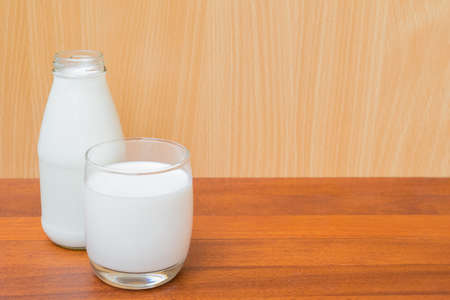 glass of milk and bottle of milk isolated on wood backgroundの写真素材
