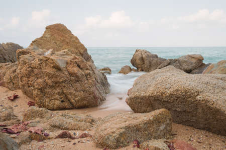 Big rock on sand and sea with low speed shutterの写真素材