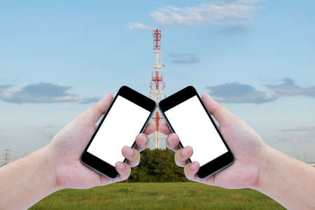 Two hand holding the black smartphone on Telecommunications tower with blue sky backgroundの写真素材