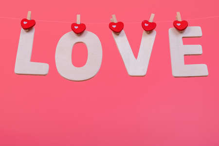 Word LOVE hang on pink color background, valentine