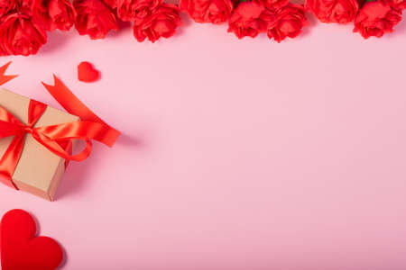 Valentines day and love concept. One small gift box with small red heart and flowers on pink backgroundの写真素材