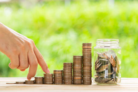 Investor business man finger walking on row of coins stack with blur green nature background. Money...