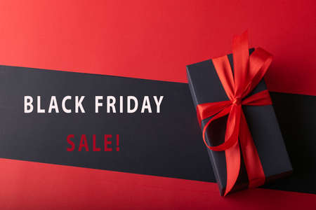 Top view of black boxes with red ribbon on black background and red background. Black Friday and...