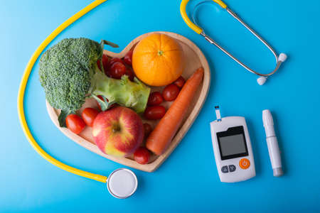 World diabetes day. National American diabetic awareness. Free Glucose Monitors on blue background. Yellow stethoscope check fruit on heart plate. Healthcare and medical conceptの写真素材