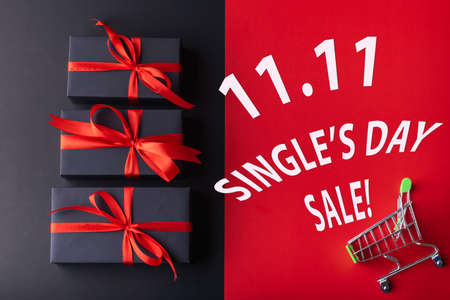 11.11 Single day sale. 3 black box with red ribbon on black color background and small cart on red color background with white 11.11 single's day sale textの写真素材