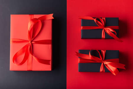 1 Big Red gift box with red ribbon on half red color background and 2 black gift box on half black...