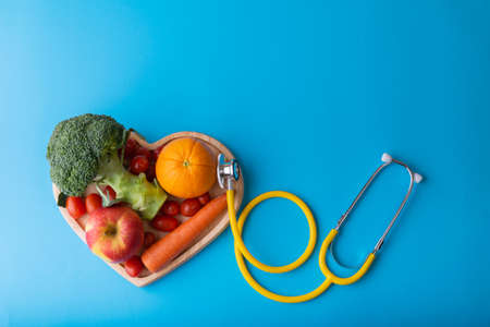 Diabetes monitor, diabetic measurement. World diabetes day concept. Yellow stethoscope check fruit on heart plate.の写真素材