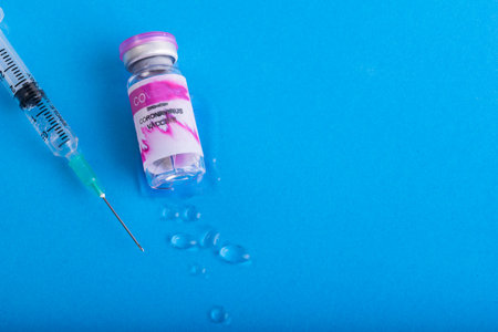 Vaccine bottle is broken for Covid-19 or Coronavirus. One syringe to get Vaccine on blue backgroundの写真素材