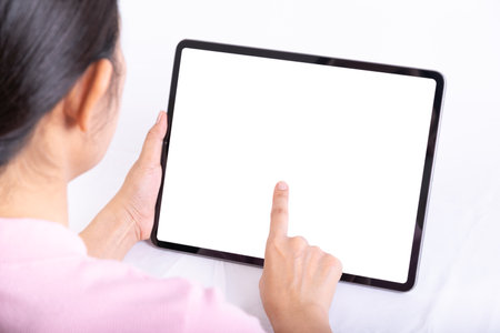 Women useing finger to touch tablet on table, tablet have white screen, rear. view from back to front of womenの写真素材