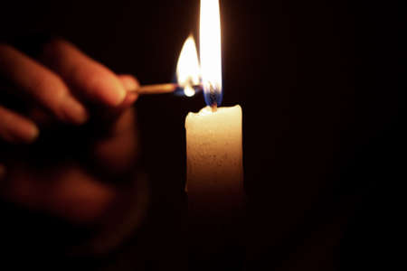 light candle with match in darknessの写真素材