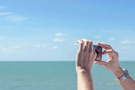 taking photo of ocean by phoneの写真素材