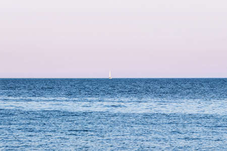 small boat in blue ocean at sunsetの写真素材