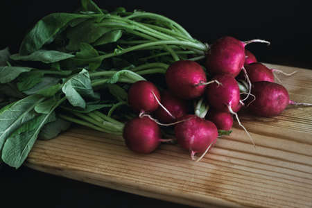 red radish on wooden board in dark