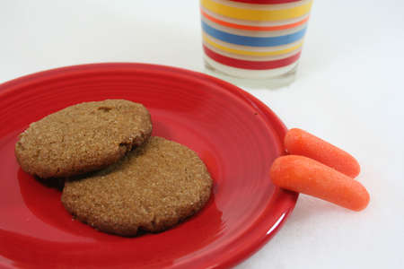 Two cookies on red plate for Santa and two carrots for reindeer with glass of milkの写真素材