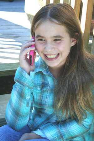 Smiling pre teen girl talking on cell phoneの写真素材