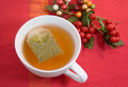 Cup of tea with holiday berries on red backgroundの写真素材
