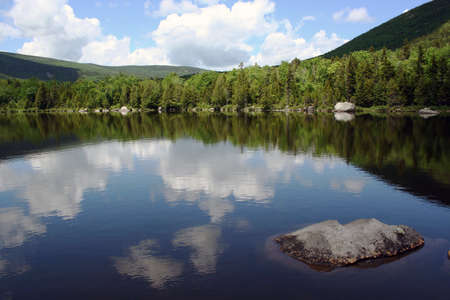 Scenic pond in Maine reflecting mountain and skyの写真素材