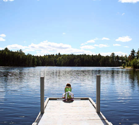 Little girl on dock at lake in Maineの写真素材