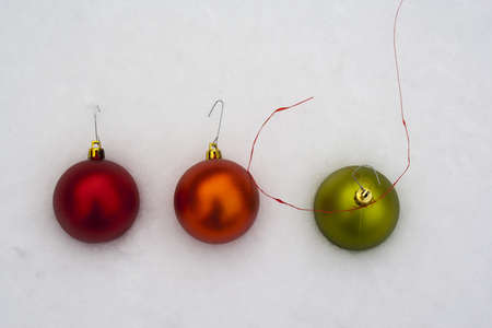 red orange and green christmas ornament in fresh snowの写真素材