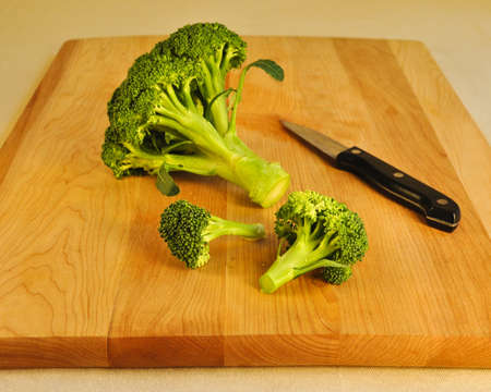 A horizontal shot of fresh green broccoli on a wooden cutting board with a paring knife の写真素材