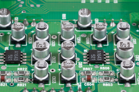Close-up of a green circuit board displaying aluminum capacitors and integrated circuits, showcasing...