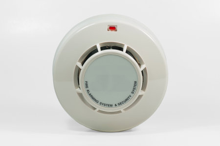 A photoelectric smoke detector features a modern design with a visible warning light and is...