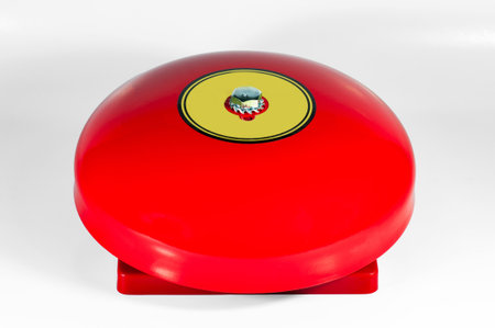 Bright red alarm bell used for signaling alerts in emergency situations and safety protocols,...