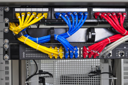 In a data center, a patch panel displays managed cables in yellow, blue, red, and gray. The vibrant...