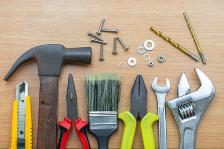 A variety of hand tools are neatly arranged on a wooden surface, including hammers, pliers, and screws for construction work.の写真素材