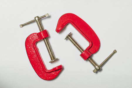 Two mini C clamps are positioned on a clean white surface, showcasing their sturdy design for...
