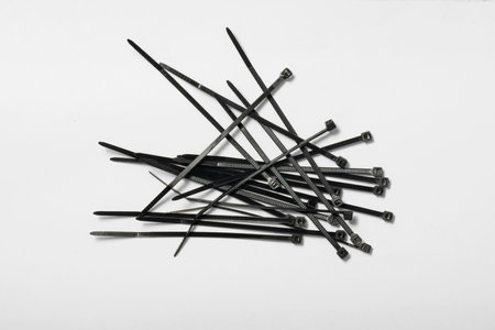 Multiple black cable ties are arranged in a random fashion isolated on white background