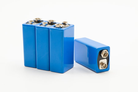 Four blue rechargeable batteries are grouped together with one positioned separately, isolated on...