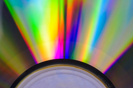 Colors reflect vividly from a DVD, forming a dynamic light spectrum with an array of hues radiating outward.の写真素材