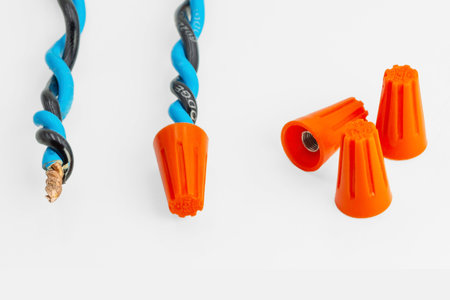 A person connects twisted wires with colorful wire connectors for safe electrical installations in a...