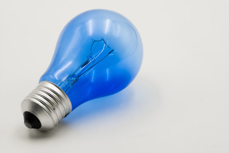 Bright blue electric light bulb positioned at an angle showcases its innovative design against a neutral backdrop.の写真素材
