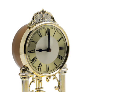 A vintage clock featuring a gold finish and Roman numerals stands elegantly against a white backdrop.の写真素材