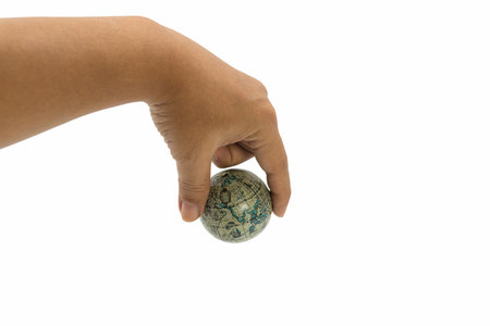 A human hand holding a small globe with an antique world map on white background, representing...