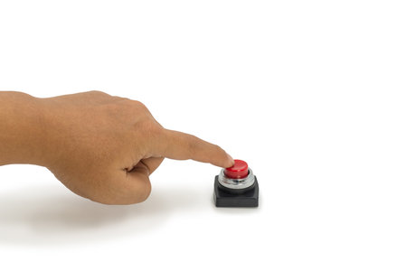 Close-up of a hand pressing a red emergency stop button on white background, symbolizing critical...