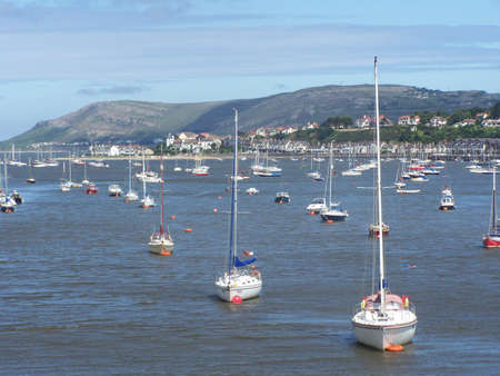Yaghts in conwy river with deganwy quay and llandudno's great orme in the background.の写真素材