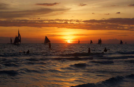 beautiful Boracay sunset with yachts and bathers swimming in the seaの写真素材